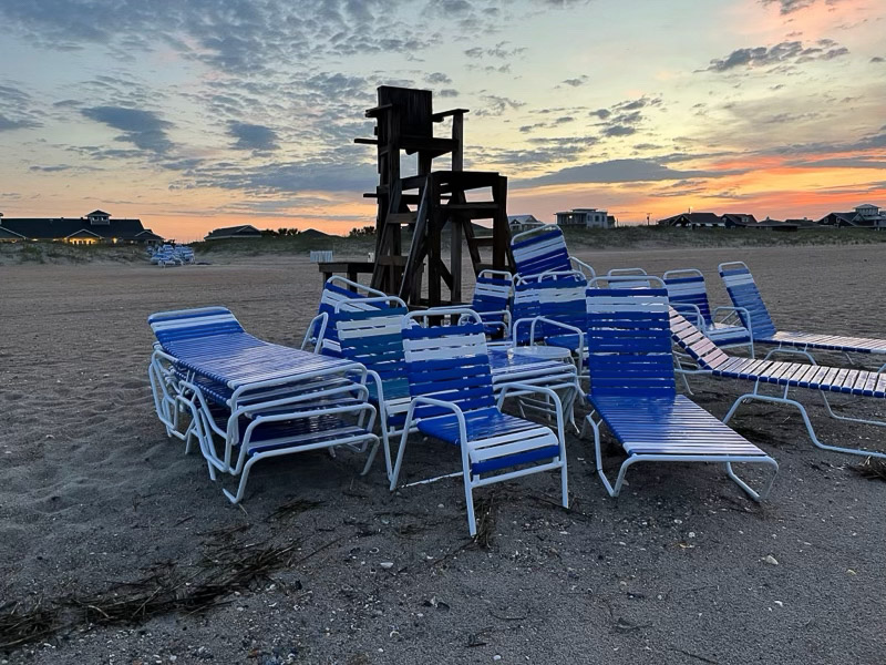 Piles of lounge chairs on the beach.