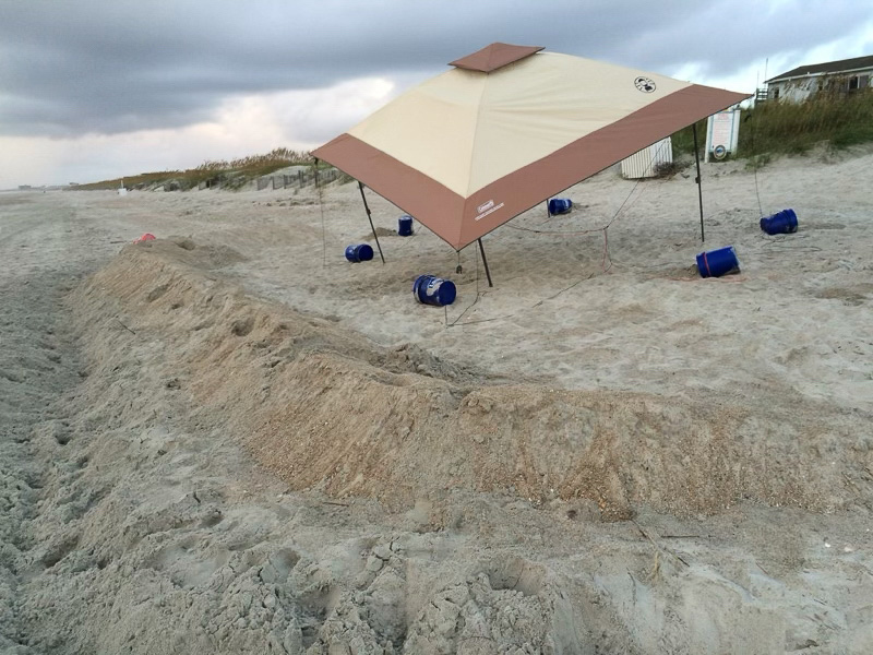 A large canopy with built up sand around it left in place overnight on the beach.