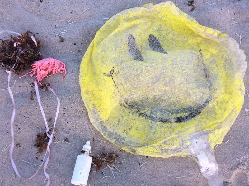 Balloon, string, and trash on a beach.
